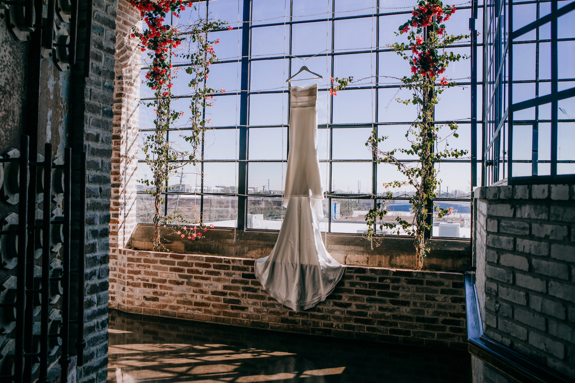 A wedding gown hangs in front of a window at a wedding venue in Houston.