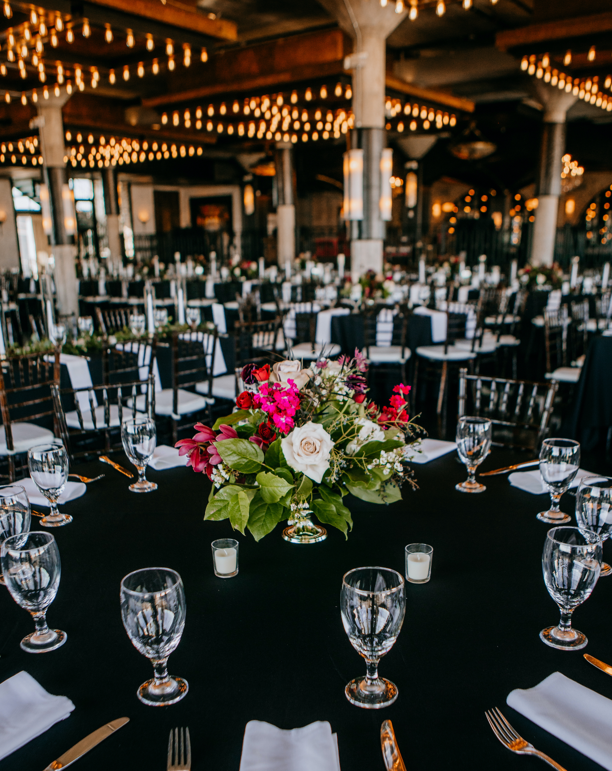 A jewel toned floral centerpiece is placed on a reception table for a Jewel Toned Wedding With Art Deco Vibes