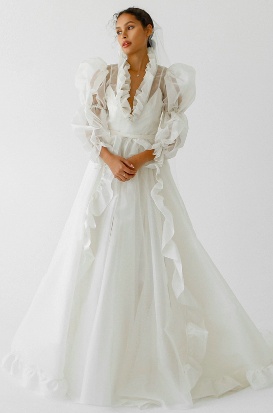 A sheer, long-sleeve flowy wedding gown designed by Odylyne the Ceremony for the spring and summer 2023.