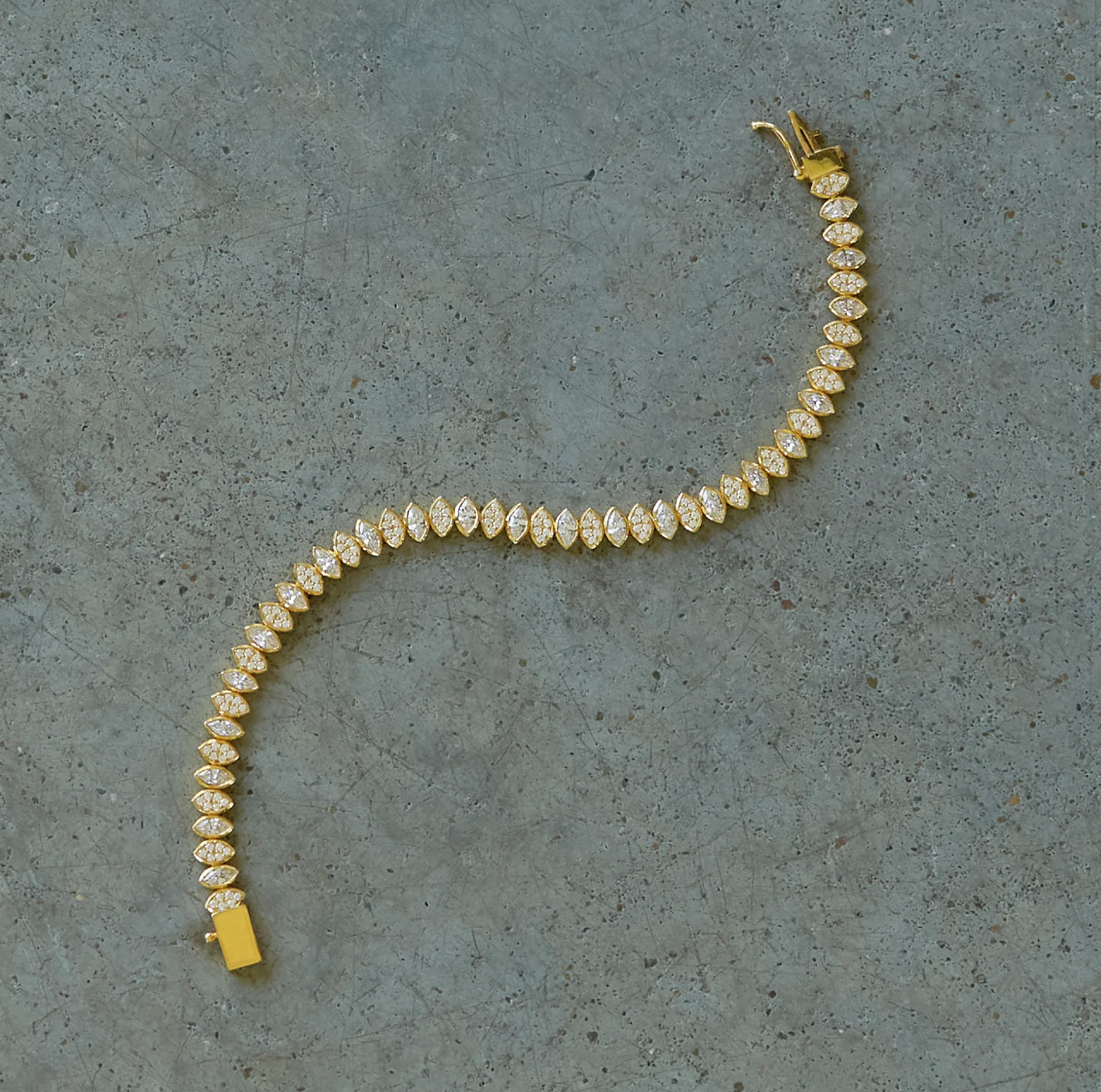 A gold, diamond encrusted bracelet lays on a table. Design by Erin Flynn Fine Jewelry.