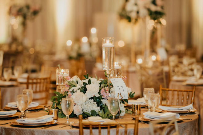 Reception table set with lit floating candles, a table number which reads "11" and a small floral centerpiece at a wedding at The San Luis Resort, Spa and Conference Center. 