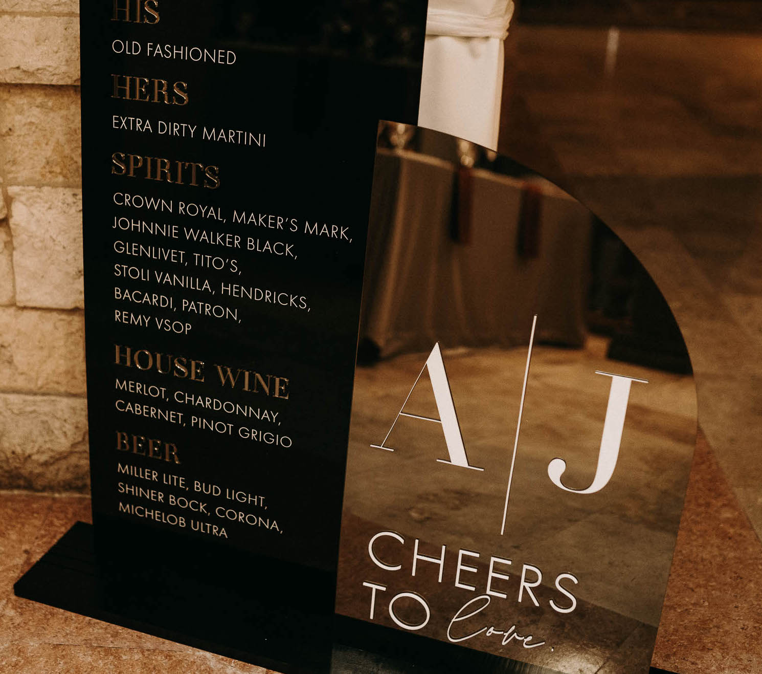 A wedding reception cocktail menu on a black display with metallic gold accents for a wedding at The Bell Tower on 34th in Houston, TX.