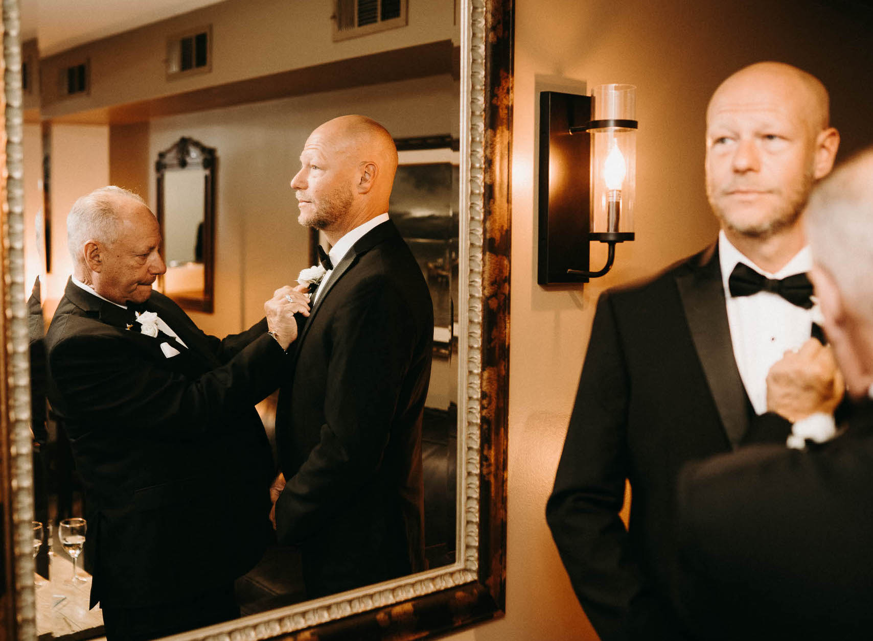 A groom's dad helps put his boutonnière on before his earthy-toned wedding at The Bell Tower on 34th in Houston, TX.