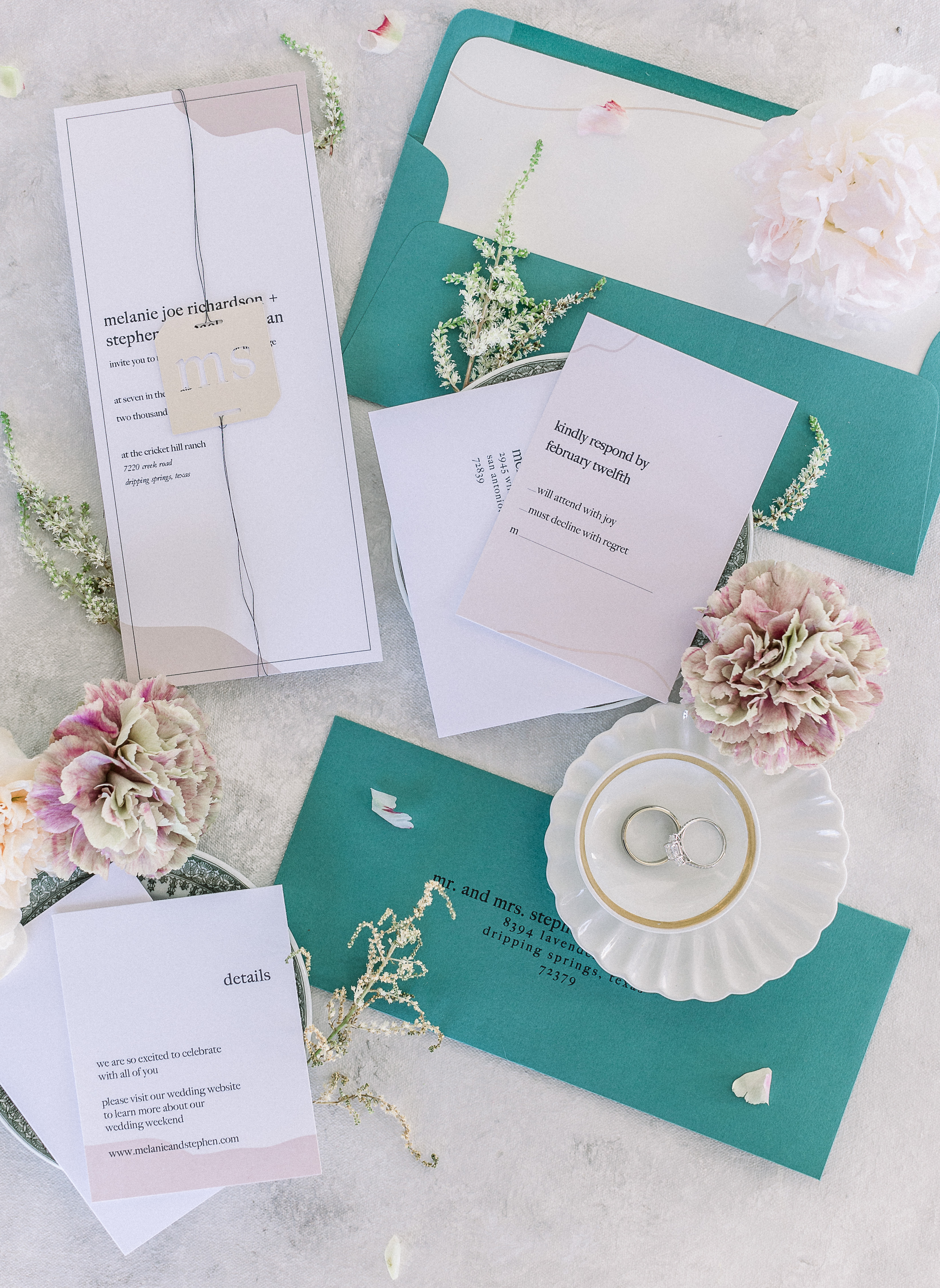 A flatlay with wedding invitations in teal and mauve hues for a hill country styled shoot at Cricket Hill Ranch in Dripping Springs, TX.