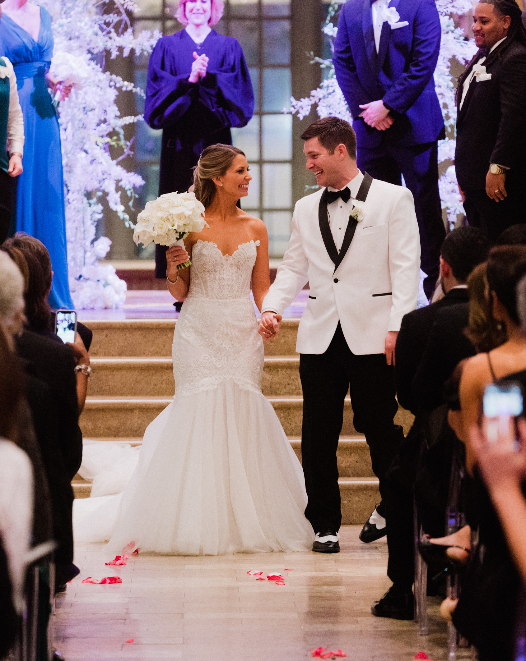 A bride and groom smile at each other and hold hands as they walk down the aisle after saying I Do.