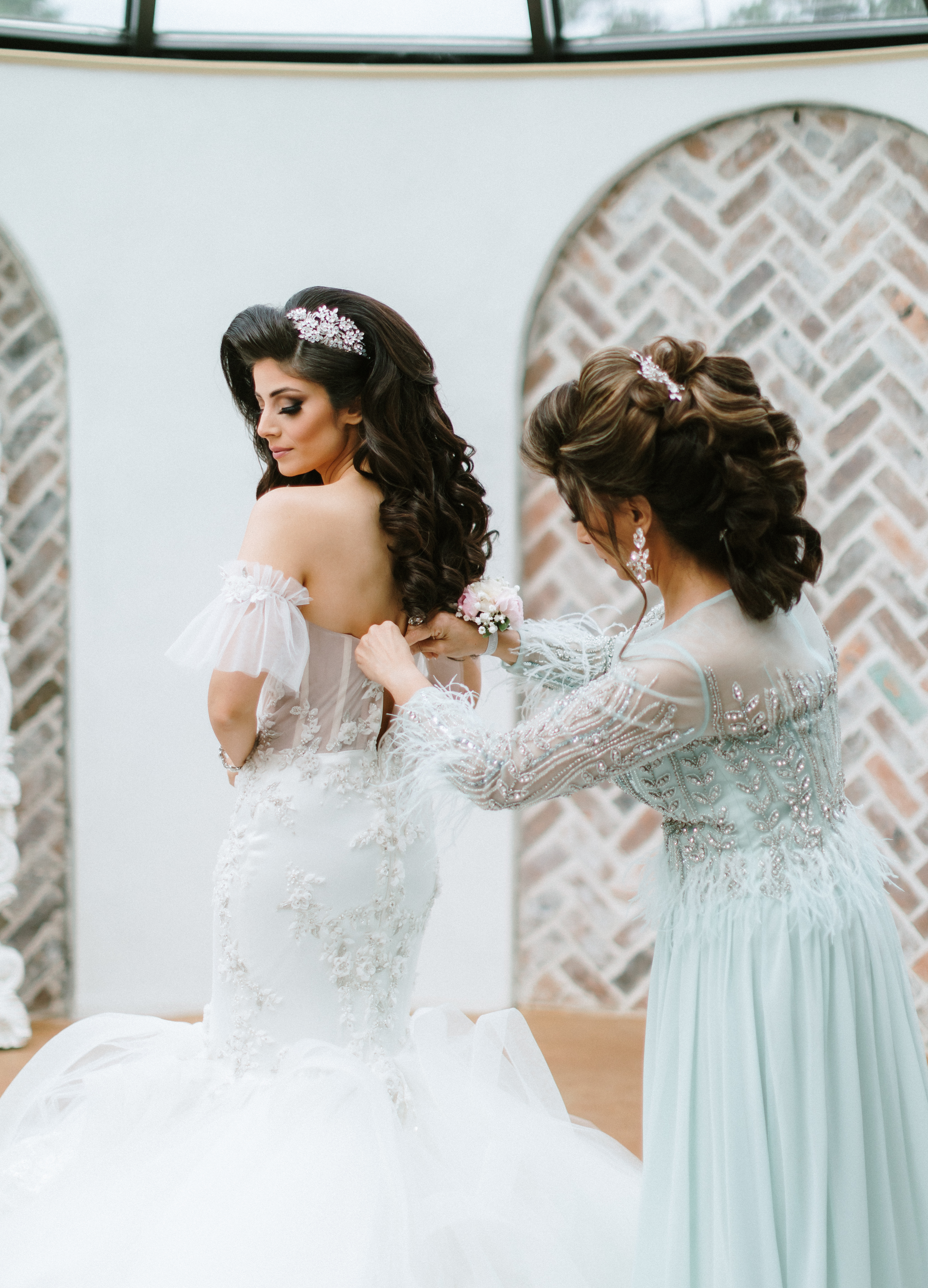 A bride's mother helps her put her dress on in the bridal suite at the wedding venue Iron Manor in Montgomery, TX.