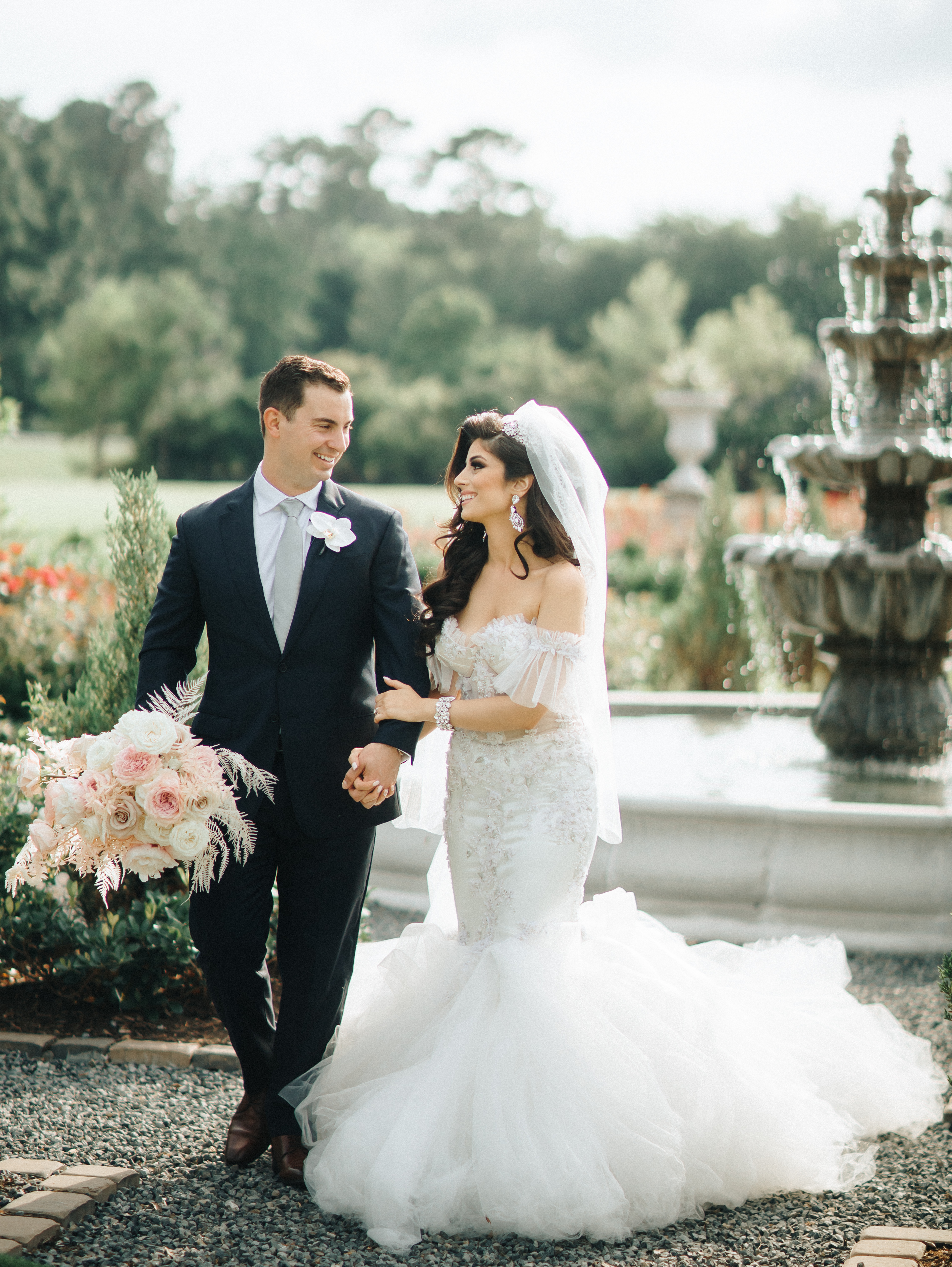 A bride and groom stand outside of a water fountain at their wedding venue in Montgomery, TX.