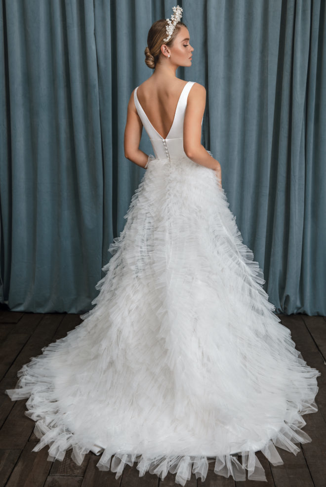 Model in a floral crown and a 2023 collection wedding dress with ruffled overskirt by Anne Barge. 