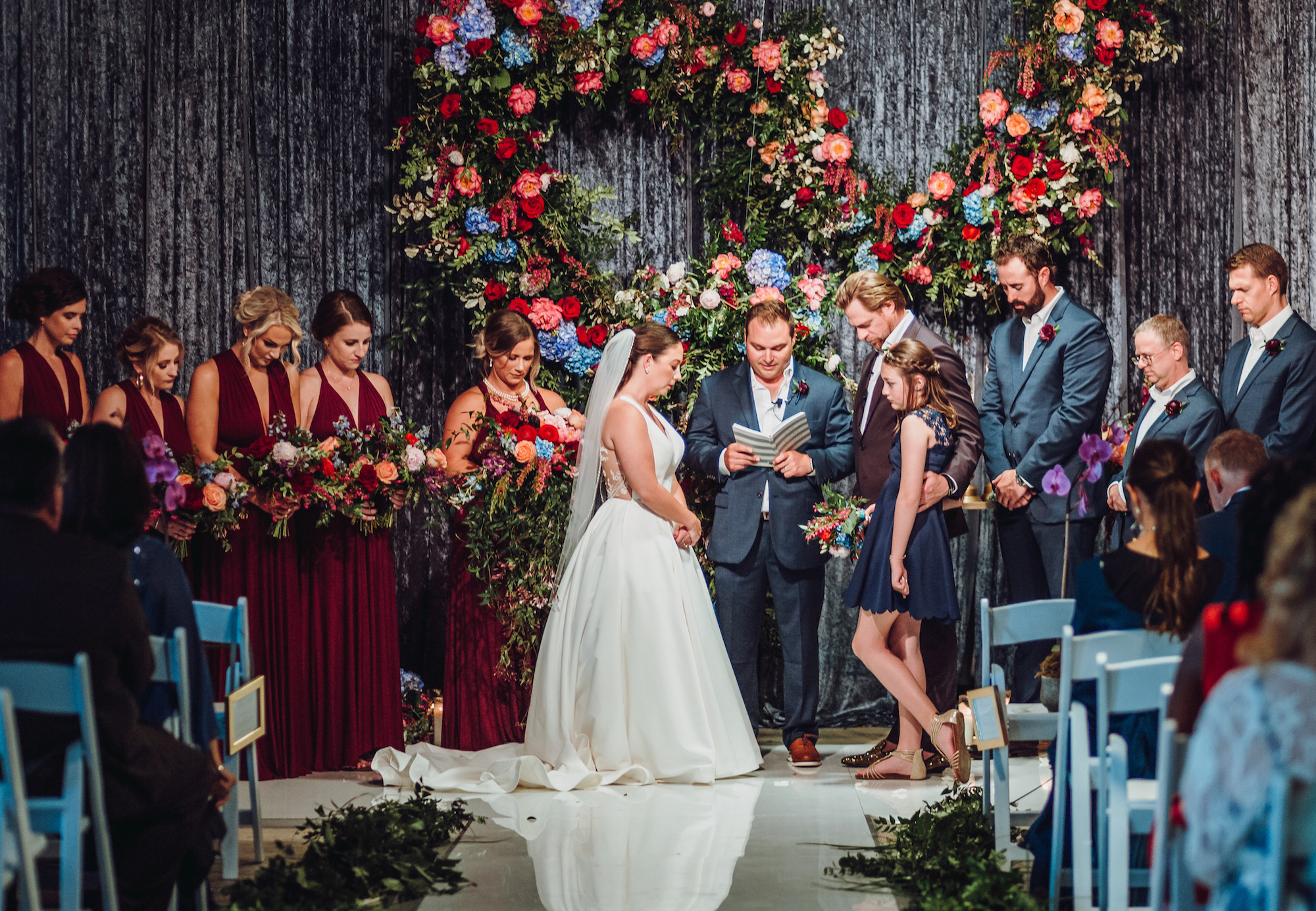 A bride and groom pray at the altar with their wedding party during their whimsical tent wedding in Houston, TX.