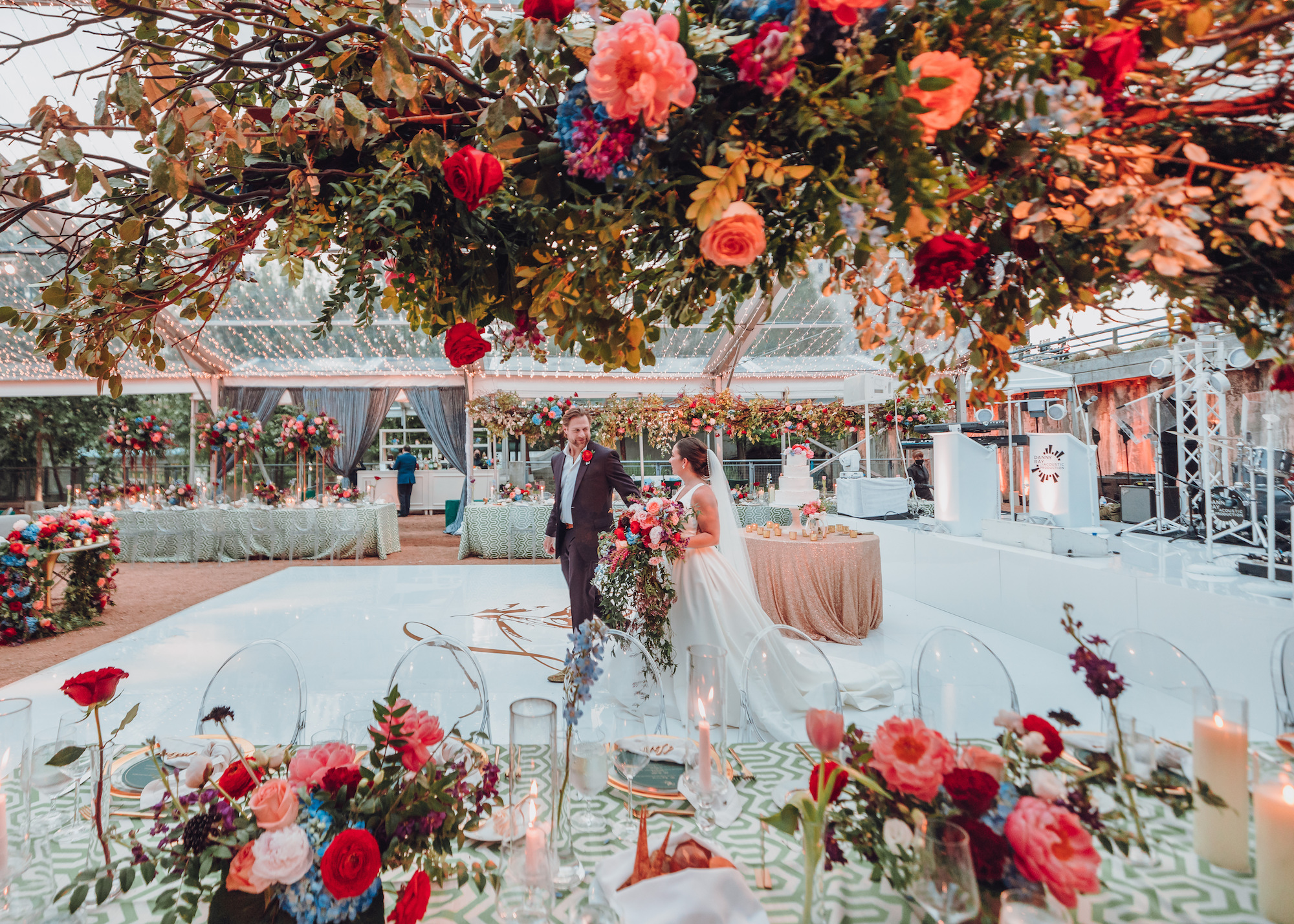 A groom walks with his bride across the dancefloor of their whimsical tent wedding before their guests arrive.