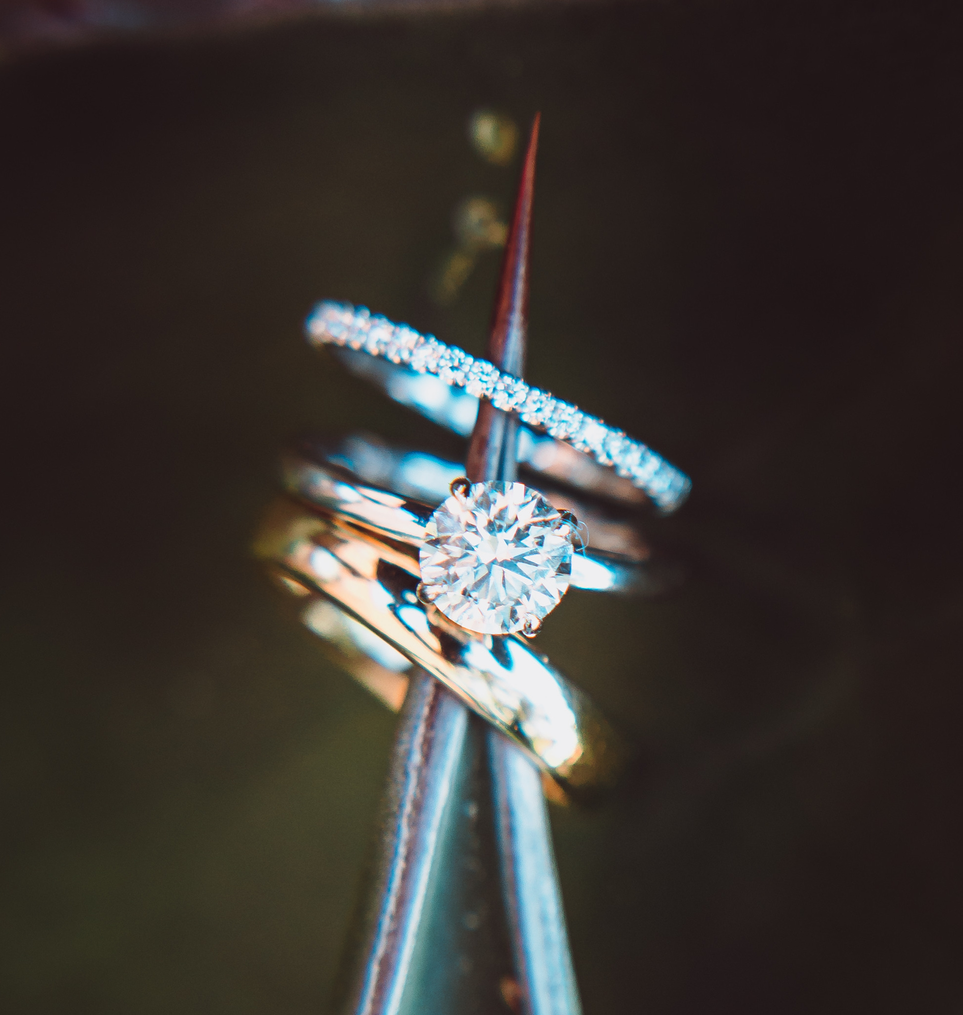 A bride and grooms wedding bands are hanging on the tip of a palm leaf for an alfresco wedding with terra cotta accents.