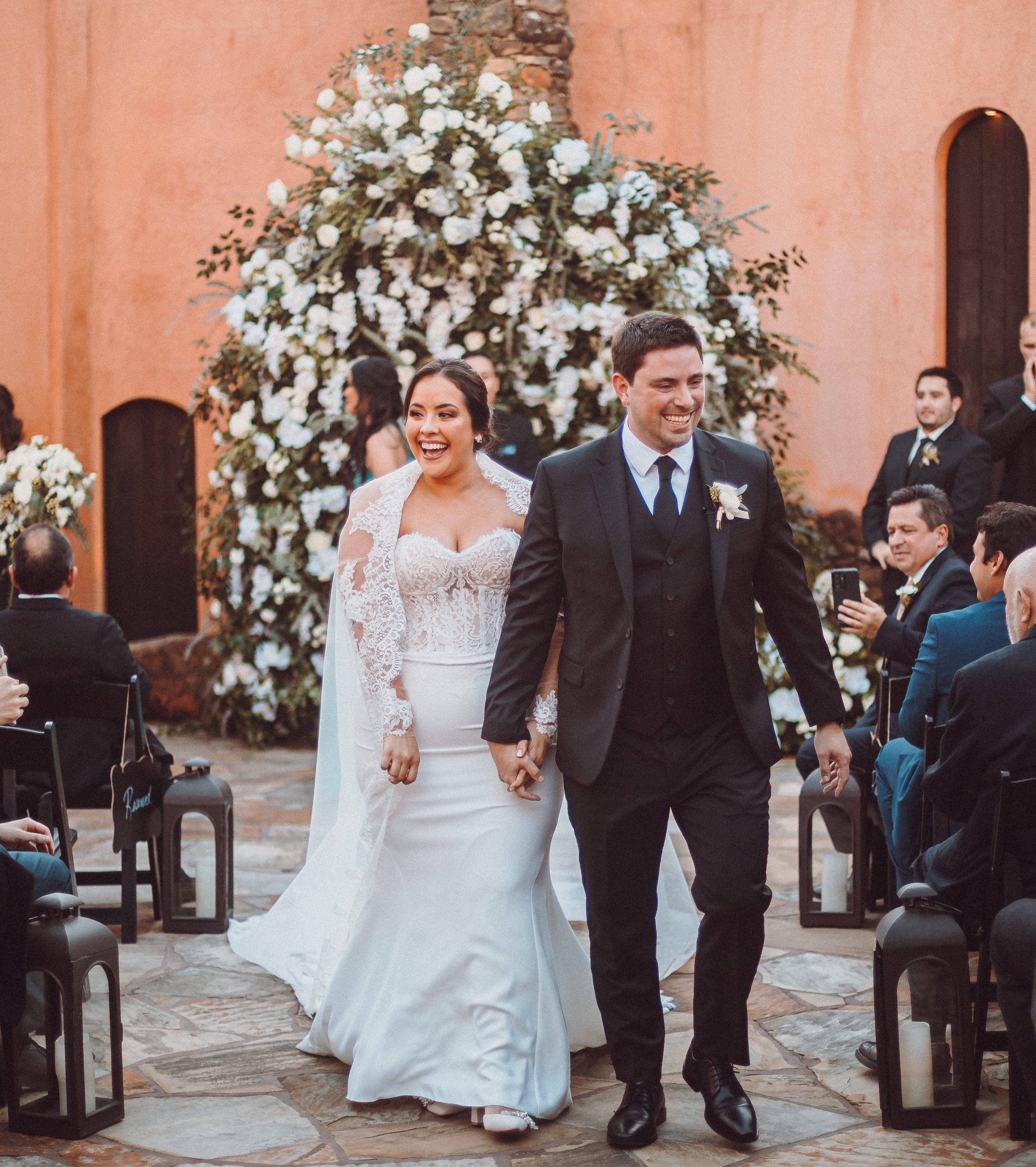 A bride and groom walk down the aisle smiling and holding hands during their wedding in Houston, TX.