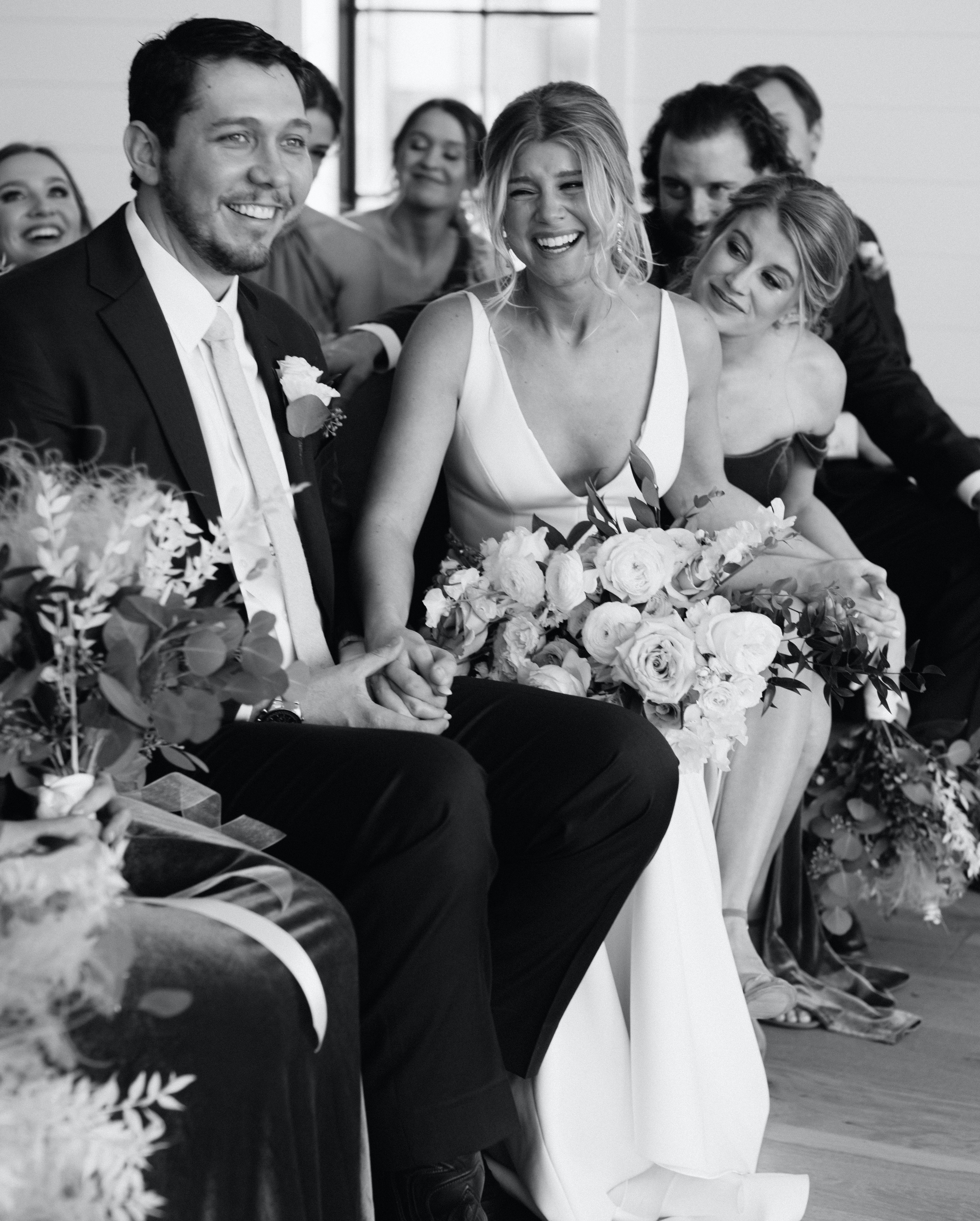 A black and white photo of a bride sitting with her groom as she smiles and cries before their wedding ceremony in Brenham, TX. Peach-Toned Countryside wedding.