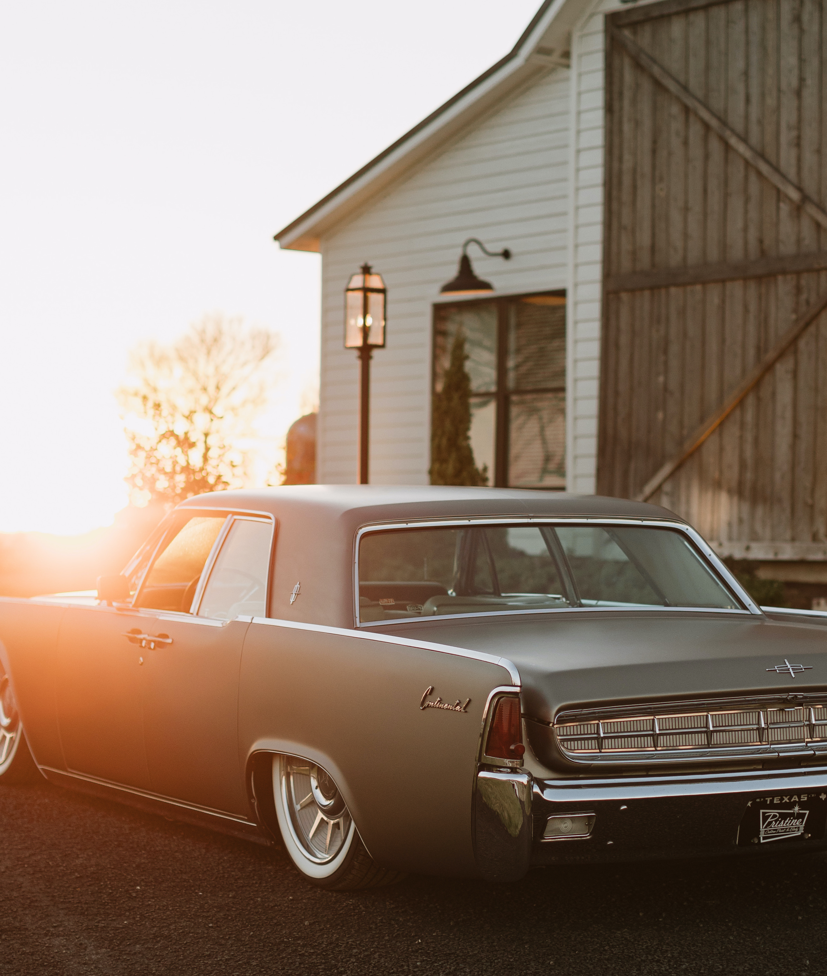 A wedding getaway vintage car is parked outside a wedding venue in Brenham, TX while the sunsets in front of it.