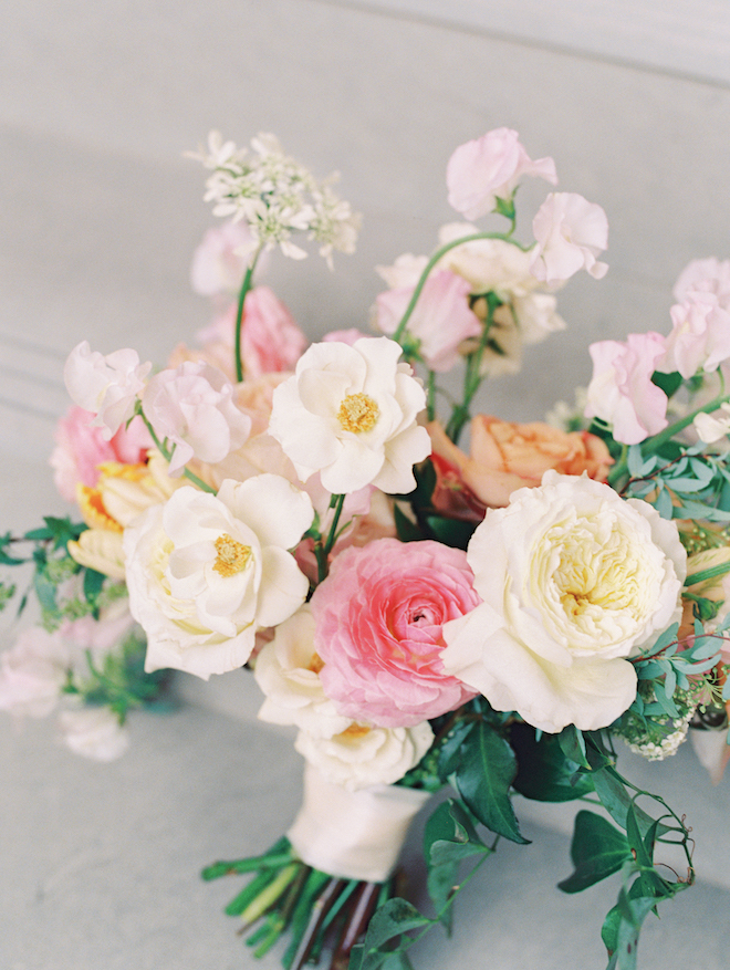 White, orange and pink pastel flowers arranged in a wedding bouquet. 