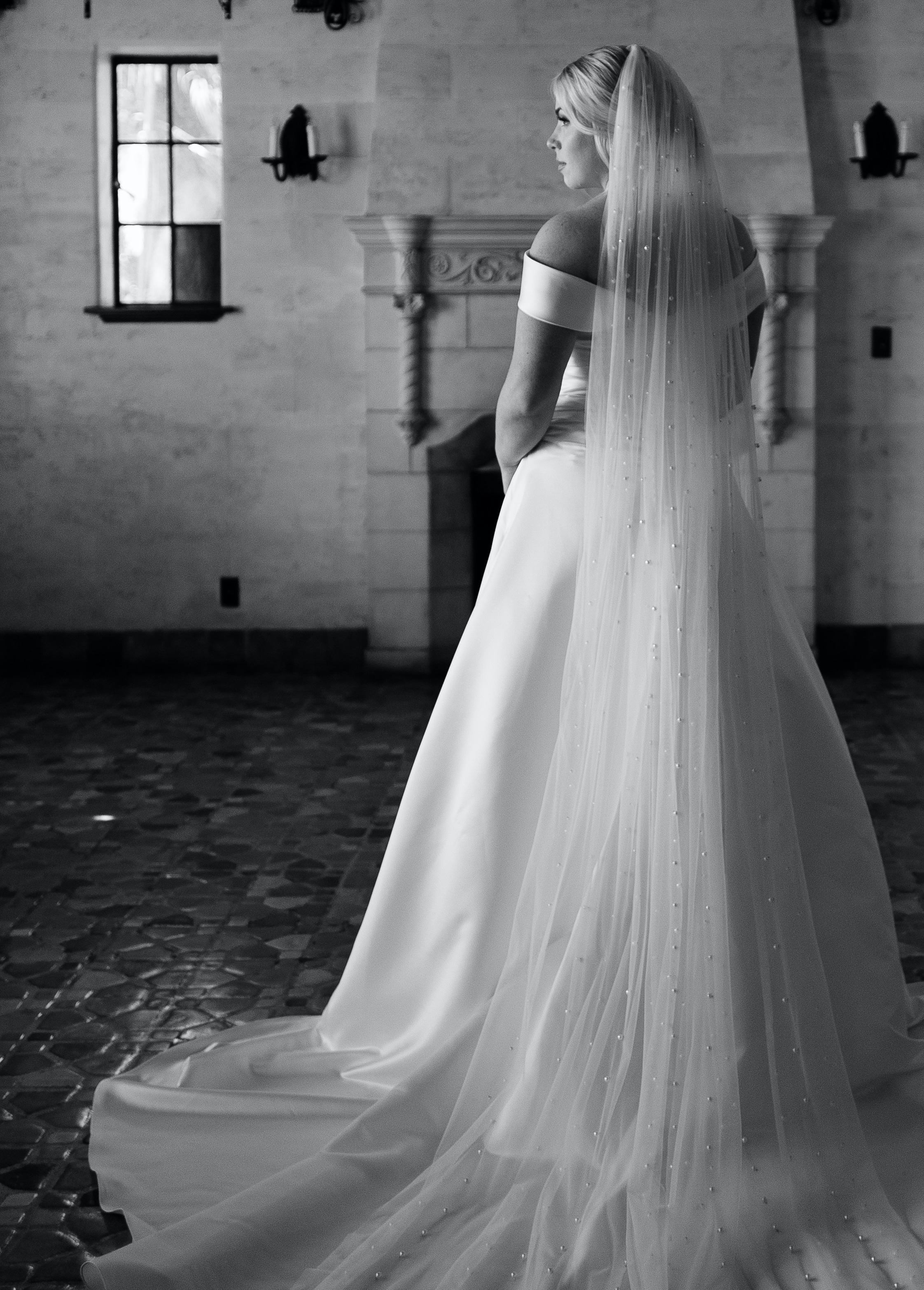 A black and white photo of a bride looking away while getting ready for her intimate summer wedding Sarasota, FL.