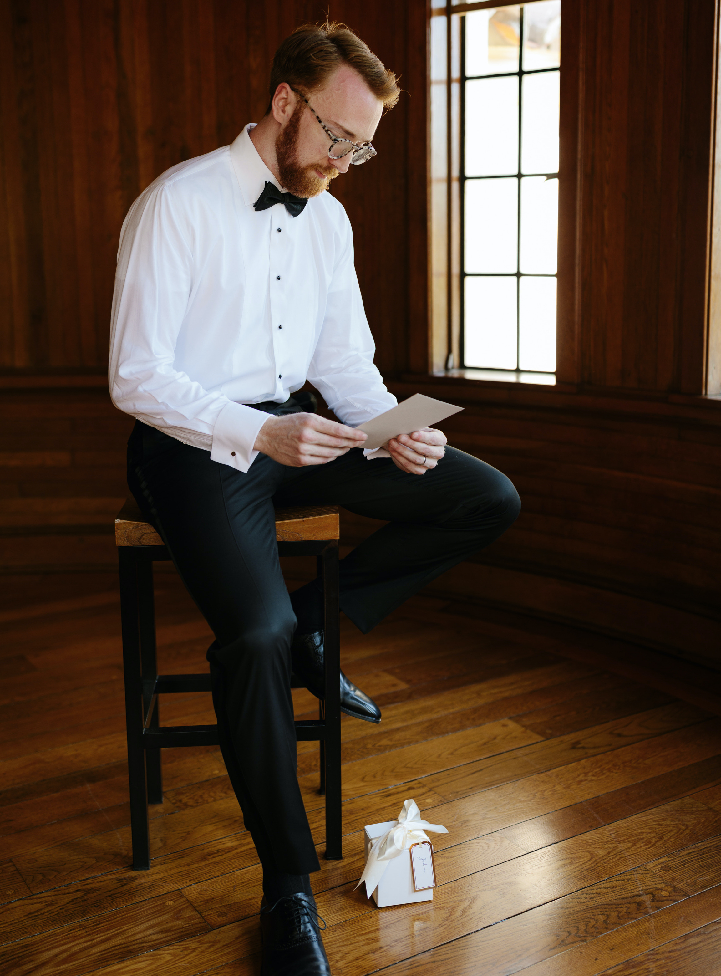 A groom looks down and reads a letter his bride wrote to him before their intimate summer wedding in Sarasota, FL.