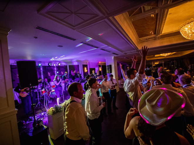 Wedding guests dance on the dance floor as the band, The Moment plays at a wedding reception. 