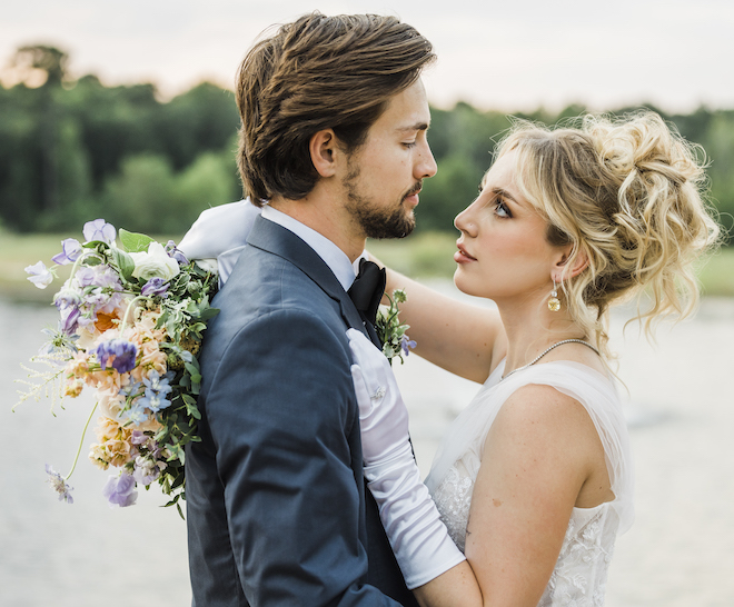 The bride holds her pastel wedding bouquet around the grooms neck as she looks into his eyes. 