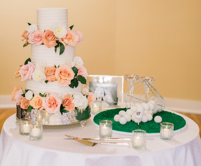 three tier wedding cake with pink, white and orange roses and cake balls replicated to look like golf balls on a bed of green icing by Sweet Treets Bakery.