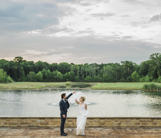 The groom spins the bride next to a pond outside the wedding venue, The Hundred Oaks. 