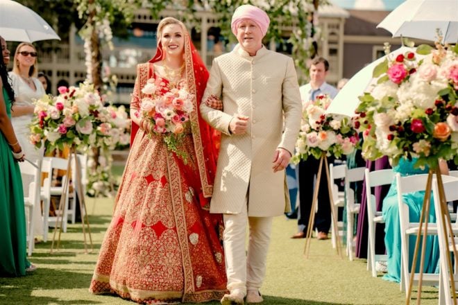 The bride and her father walking down the aisle in traditional Indian clothing.