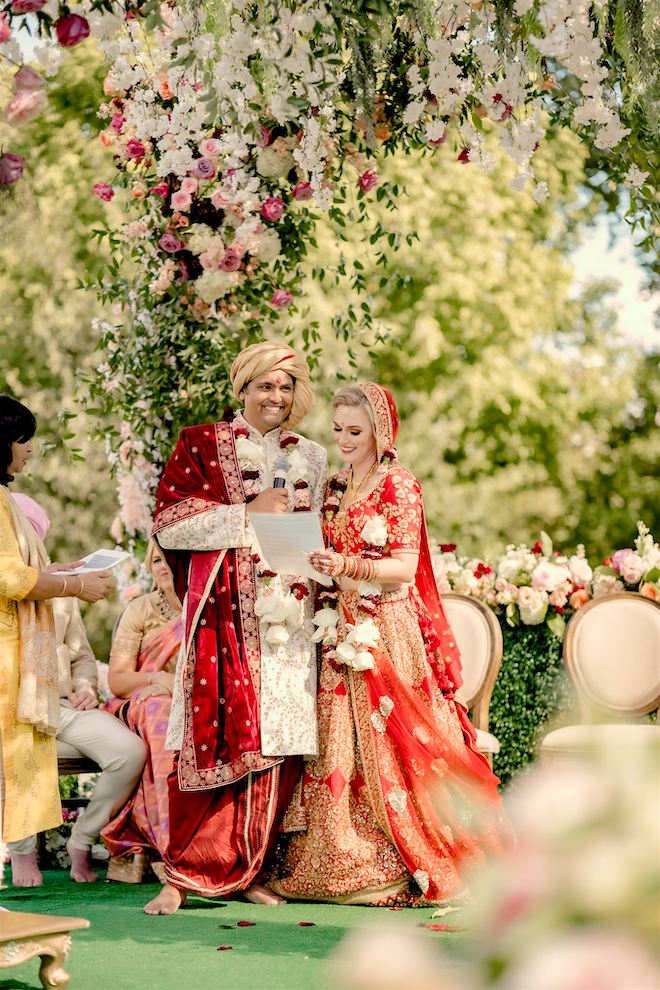 Smiling bride holding a piece of paper while the groom holds a microphone under a Bloom Filled setting