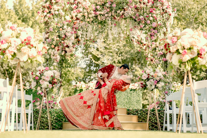 The groom dips the bride while kissing her after getting married.