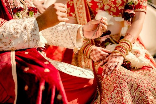 A close-up of the groom holding a necklace during their Indian Fusion wedding ceremony.