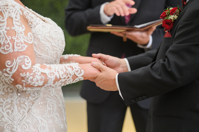 The bride and groom hold hands as they share vows at the alter at their wedding venue, Sam Houston Hotel. 