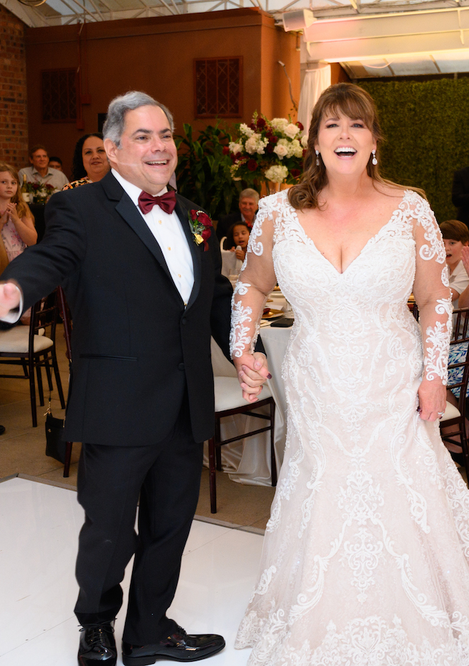 The bride and groom laugh and hold hands on the dance floor at their wedding reception at the Sam Houston Hotel. 