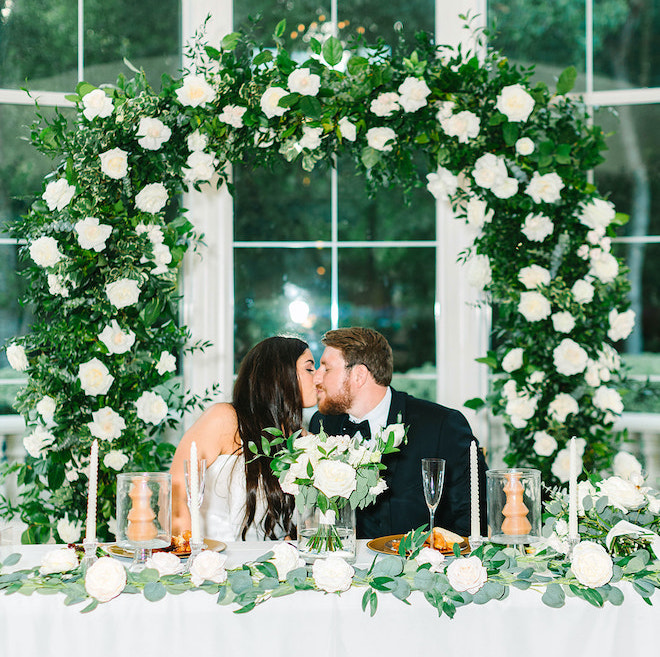 The bride and groom kissing under the altar at their reception.