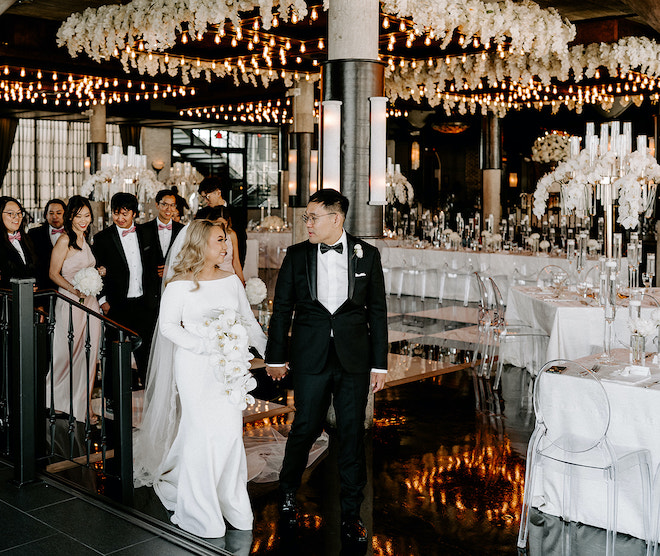 Bride and groom walk hand in hand during their wedding reception at The Astorian wedding venue. 