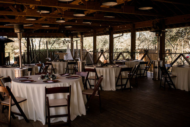 The reception tables with white tablecloths and wood chairs for the rustic chic wedding.