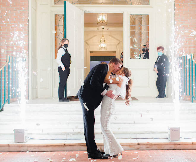 Bride and groom kiss in the middle of two cold spark fireworks after their black tie wedding in Houston.