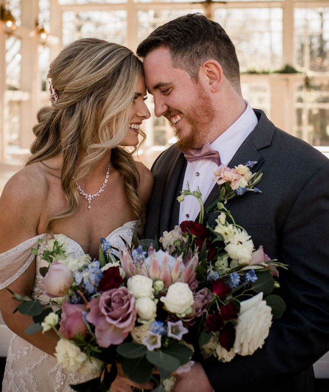 The bride and groom smiling at each other with the brides vintage chic bouquet.