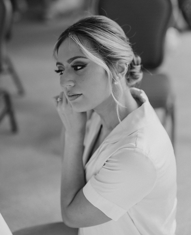 A bride with a low up-do puts on a pearl earring before her wedding ceremony in Houston. 