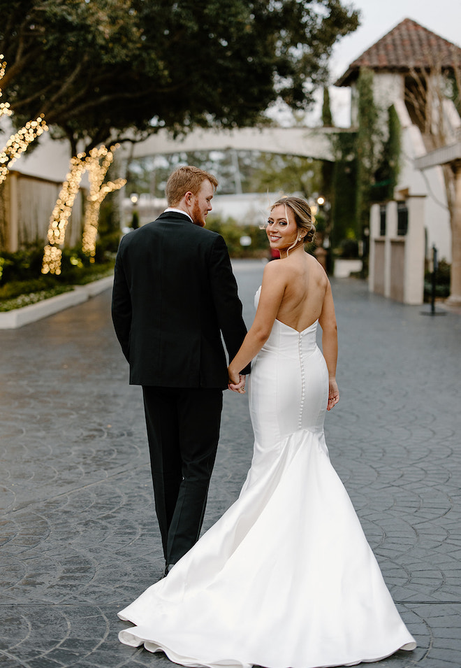 Groom holds the hand of a bride in a strapless gown at their black and white wedding reception at The Bell Tower on 34th. 