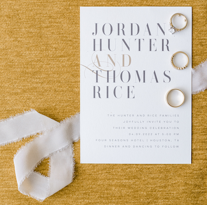 The wedding invitation and rings with a golden yellow background. 