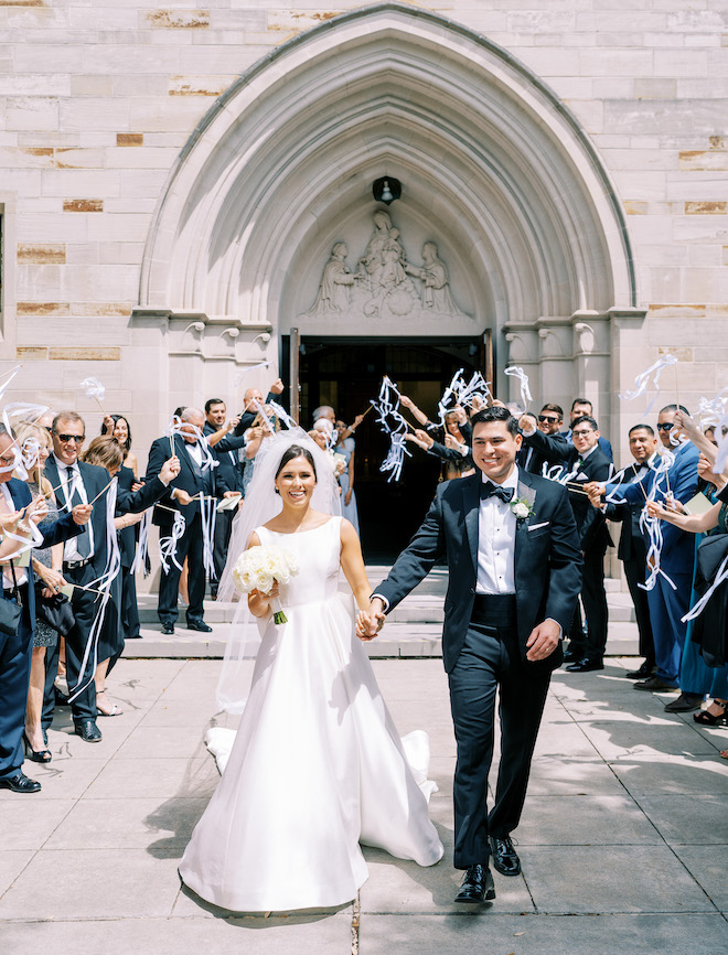 The bride and groom walking out of their wedding ceremony holding hands. 