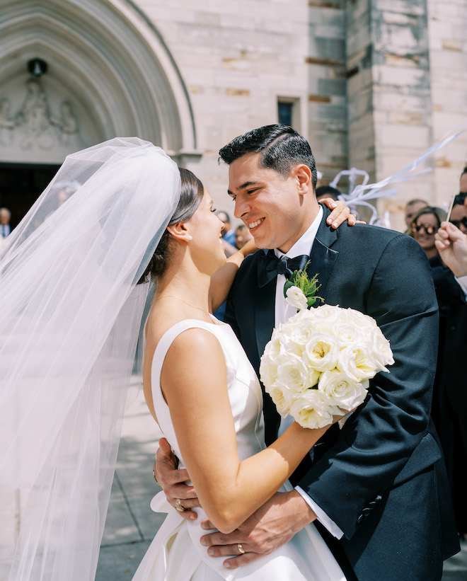 The bride and groom smiling at each other after their wedding ceremony.