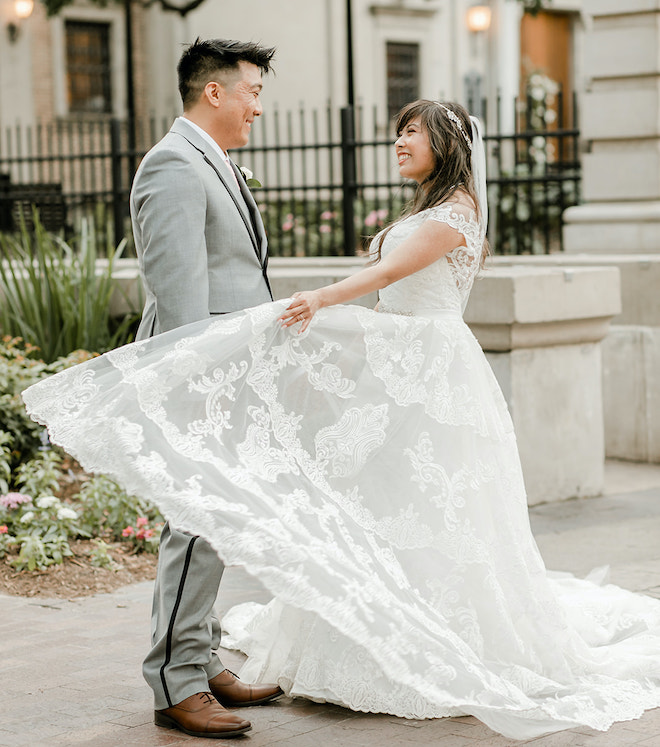 The bride and groom smiling as the bride twirls her dress. 