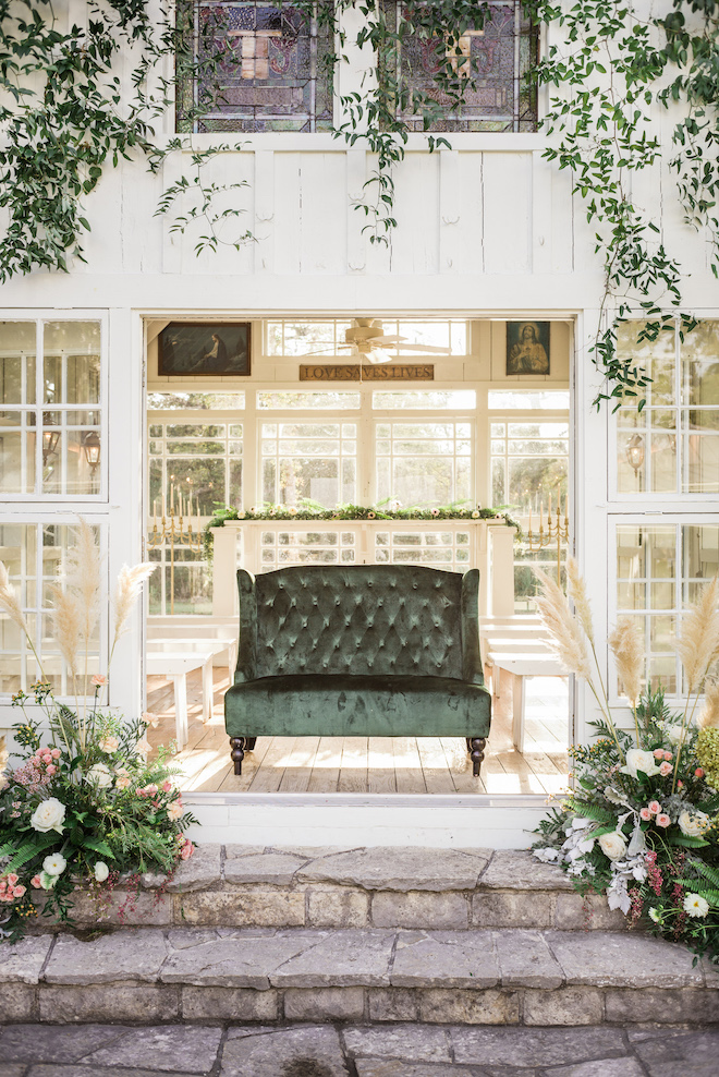 An emerald green velvet loveseat in the chapel.