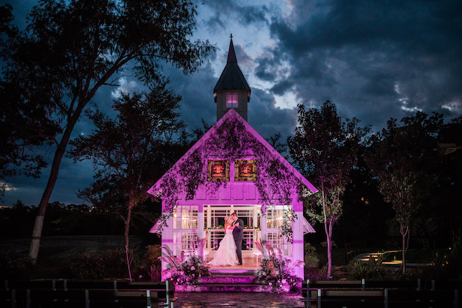 Bride and groom dancing in the purple lit-up chapel at night.