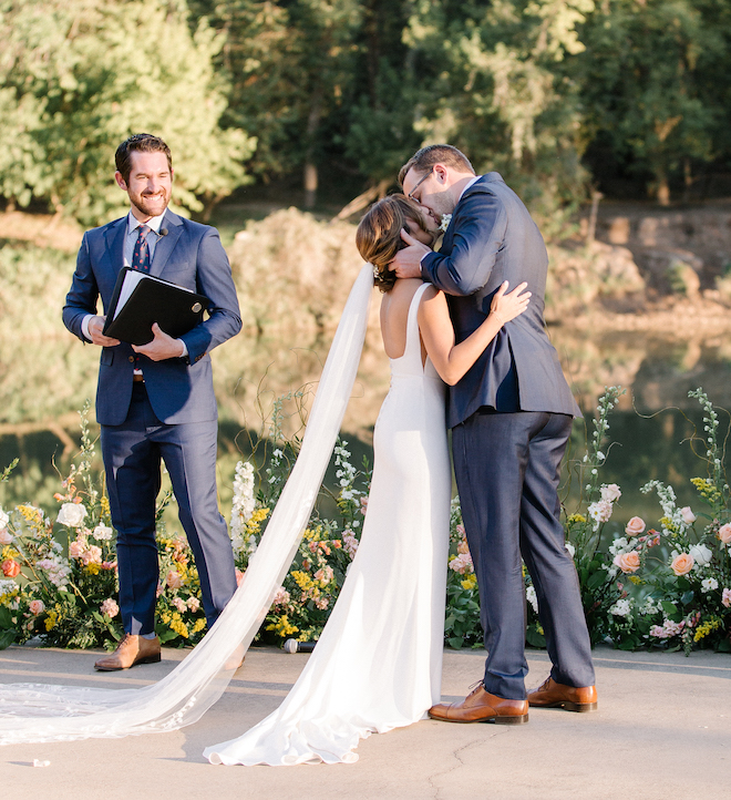 The bride and groom kissing at their wedding ceremony, with the Colorado river in the background. 