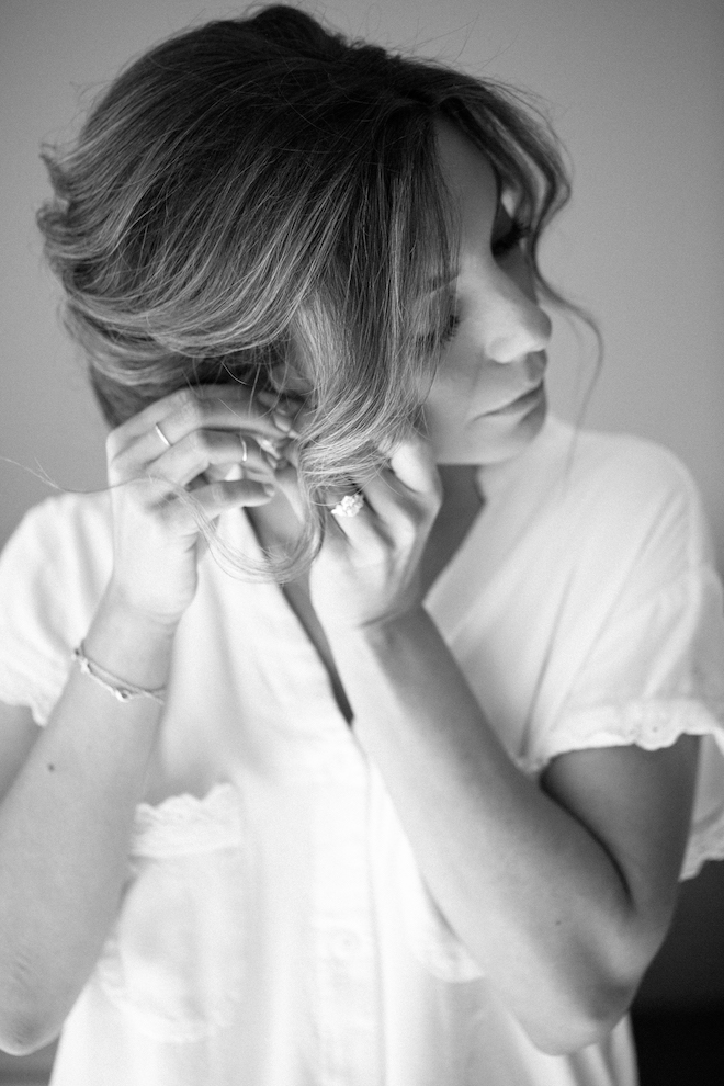 A bride putting on an earring as she gets ready for her fall wedding.