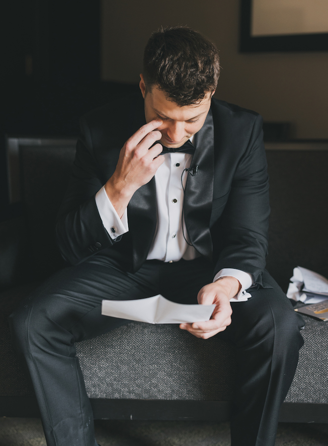 The groom wiping his eye as he reads a letter.