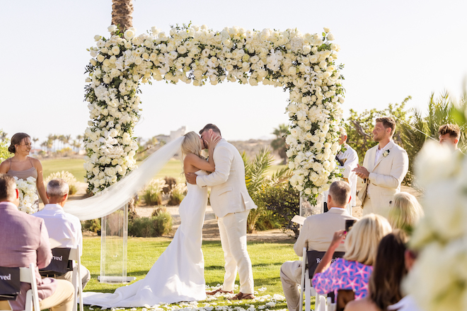 The bride and groom kissing at their tropical destination wedding ceremony.