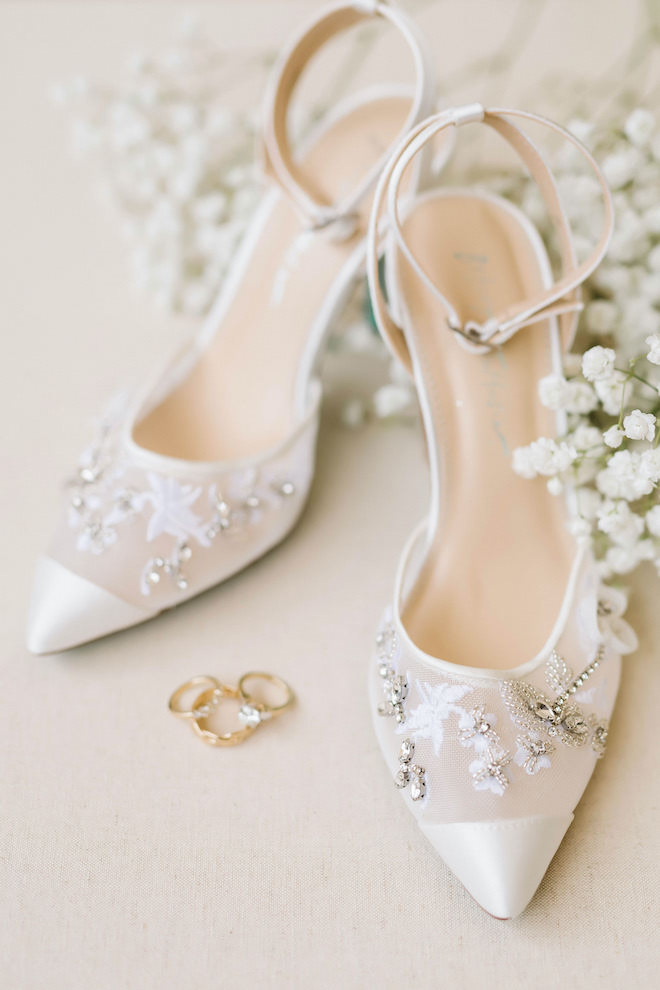 Bridal shoes surrounded by baby's breath florals and gold wedding bands.