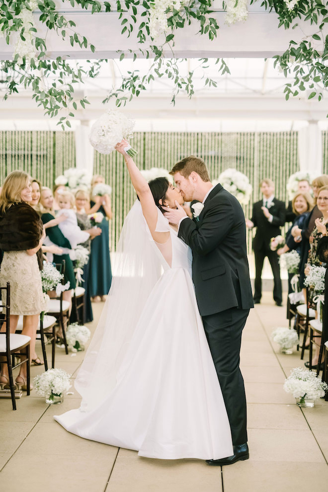 The bride and grooming kissing as they walk back down the aisle at a downtown boutique hotel.